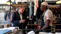 Minisitiri w'ububanyi n'amahanga w'Amerika Antony Blinken (ibumoso) ari kumwe n'umucuruzi w'imyenda i Johannesburg muri Afurika y'epfo
