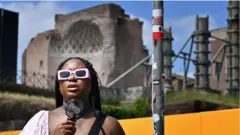 Una mujer se acerca un ventilador pequeño a la cara. 