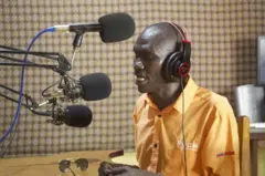 Charlemagne Laoumbaï présente son émission 'Echos pour les handicapés' au studio de Radio ESCA.
