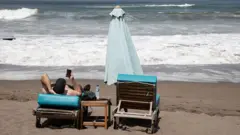 Turis sedang bersantai di Pantai Berawa, Canggu, Bali