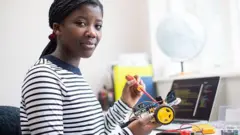 Young girl wey wear balck and white stripe cloth wey hold toy car for had and screwdriver for science lesson class