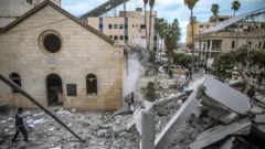 يمرّ الناس أمام مبانٍ متضررة وأنقاض مستشفى المعمدانيين في مدينة غزة