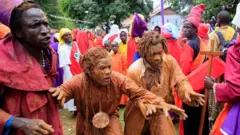 Men cover themselves in mud to attend a Christmas Day procession near Ugunja, in Siaya County, Kenya