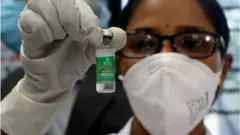 কোভিশিল্ড দেখাচ্ছেন একজন ভারতীয় স্বাস্থ্যকর্মী