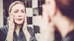 Mujer mirándose al espejo.