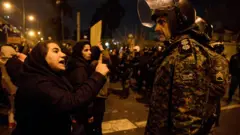 A woman attending a vigil in Tehran for those killed in the Ukraine International Airlines plane crash confronts a policeman (11 January 2020)