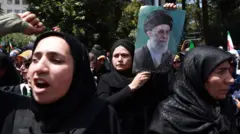 Mujeres en una protesta en Teherán contra Israel, una de ellas porta una imagen del líder supremo de Irán, Alí Jamenei