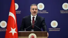Dışişleri Bakanı Hakan Fidan, Dışişleri Bakanlığı logolu podyumda açıklama yaparken. 