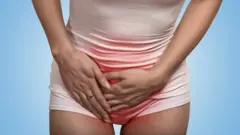 Mujer con las manos sobre sus genitales en señal de dolor.