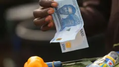 Wani mutum riƙe da takardun naira