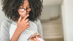 Adolescente utilisant un smartphone à la maison