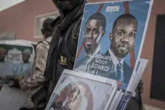 Un vendeur propose des produits dérivés en soutien à Ousmane Sonko, chef de l'opposition sénégalaise, et à Bassirou Diomaye Faye, candidat à la présidentielle, devant le lieu d'une conférence de presse à Dakar, au Sénégal, le vendredi 15 mars 2024. 