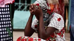 Kaba, a mother of a 10-day-old baby, reacts as she sits outside the hospital on 26 May.