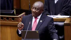 Perezida w'Afurika y'epfo Cyril Ramaphosa arimo kuvuga ijambo asoma kuri iPad