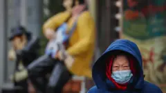 A woman wearing protective face mask walks on the street during pandemic of SARS-CoV-2 coronavirus in Moscow, Russia 18 November 2020