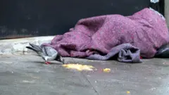 Morador de rua se abriga do frio em 28 de julho em SP