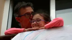 A man kisses his daughter after applauding in support of health workers,