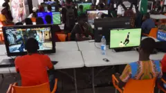 Des gamers assis devant des écrans pendant le festival de l'électronique et des jeux vidéo d'Abidjan.