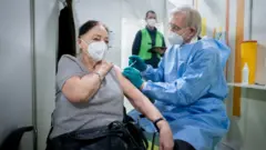 Doctor Christopher Rommel vaccinates 88-year-old Anneliese Spies with a Biontech/Pfizer vaccine against Covid-19 in Berlin