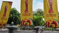 امرأة تسير أمام لافتات كأس العالم لكرة القدم تحت 20 سنة في إندونيسيا في جاكرتا في 30 مارس/آذار 2023