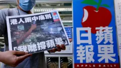 一位香港《蘋果日報》員工手持最後一份《蘋果日報》拍照留念（24/6/2021）