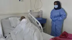 ممرضة تقف إلى جوار مريض في إحدى المستشفيات