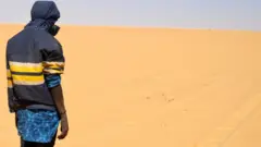 Un migrant se tient dans le désert vers le poste frontière libyen de Gatrone. (Image d'archives)
