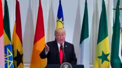 Donald Trump speaks with African flags in the background