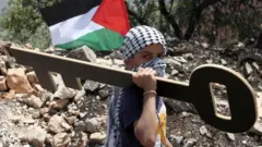 Palestinac nosi praćku na protestu kojim se obeležava 70-godišnjica Nakbe, na granici između Izraela i Gaze, 14. maja 2018