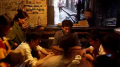চীনের একটি গ্রামে পরিবারের সদস্যরা তাস খেলছেন