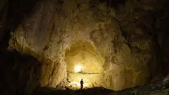 Человек стоит внутри пещеры.