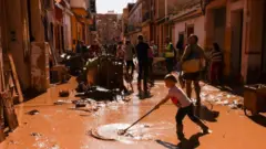 Gente barriendo el lodo de una calle de Valencia. 