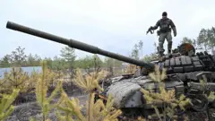 A Ukrainian serviceman stands on the turret of a destroyed Russian army tank not far from the Ukrainian capital of Kyiv on April 3, 2022