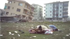 Unos hombres rezan frente a unos edificios destruidos por el terremoto de Izmit de 1999.