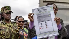 A Senior Independent Electoral and Boundaries Commission (IEBC) official shows a sample ballot paper after the opening of a container with official electoral material to be deployed in different polling stations at a tallying centre in Nairobi, Kenya.