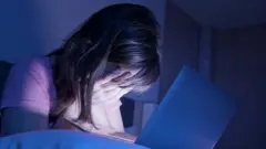 ল্যাপটপের সামনে একজন বিব্রত ও হতাশাগ্রস্ত নারী