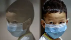 Un enfant portant un masque facial à l'aéroport international Ninoy Aquino de Manille