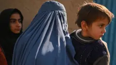 अफ़ग़ानिस्तान की एक महिला और उनकी गोद में बच्चा