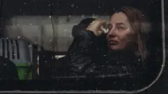 Une femme essuie une larme dans un train.