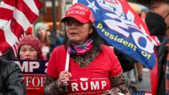 Militante de Donald Trump con camiseta, gorro y bandera alusivos al expresidente afuera de la oficina del fiscal de distrito de Manhattan en la ciudad de Nueva York el 3 de abril de 2023.