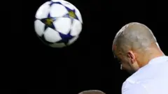 सिर से फुटबॉल मारने की कोशिश करता एक खिलाड़ी