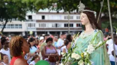 Mulher negra observa estátua de Iemanjá