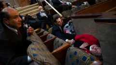 El representante Jason Crow (centro), quien fue miembro del Ejército de Estados Unidos, reconforta a la representante Susan Wild, mientras los seguidores de Trump irrumpían en la sede del Congreso.