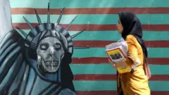 Una mujer iraní pasa frente a un mural antiestadounidense