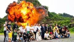 Grupo posa em frente a uma explosão