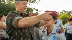 Militar colocando uma boina vermelha em uma aluna do colégio Vila Militar, de Curitiba