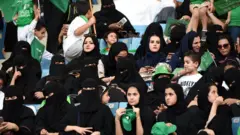 سعوديات يتابعن مباراة لكرة القدم بعد السماح لهن بذلك ضمن خطة إصلاحية لولي العهد السعودي محمد بن سلمان.