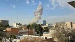 建物が立ち並ぶ市街地の奥で白い大きな煙が上がっている