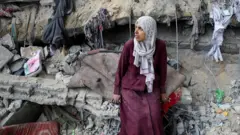 Palestinska žena sedi na ruševinama
