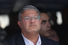 Portret izraelskog ministra sa naočalama dok gleda u daljinu, ima belu košulju i crni sako